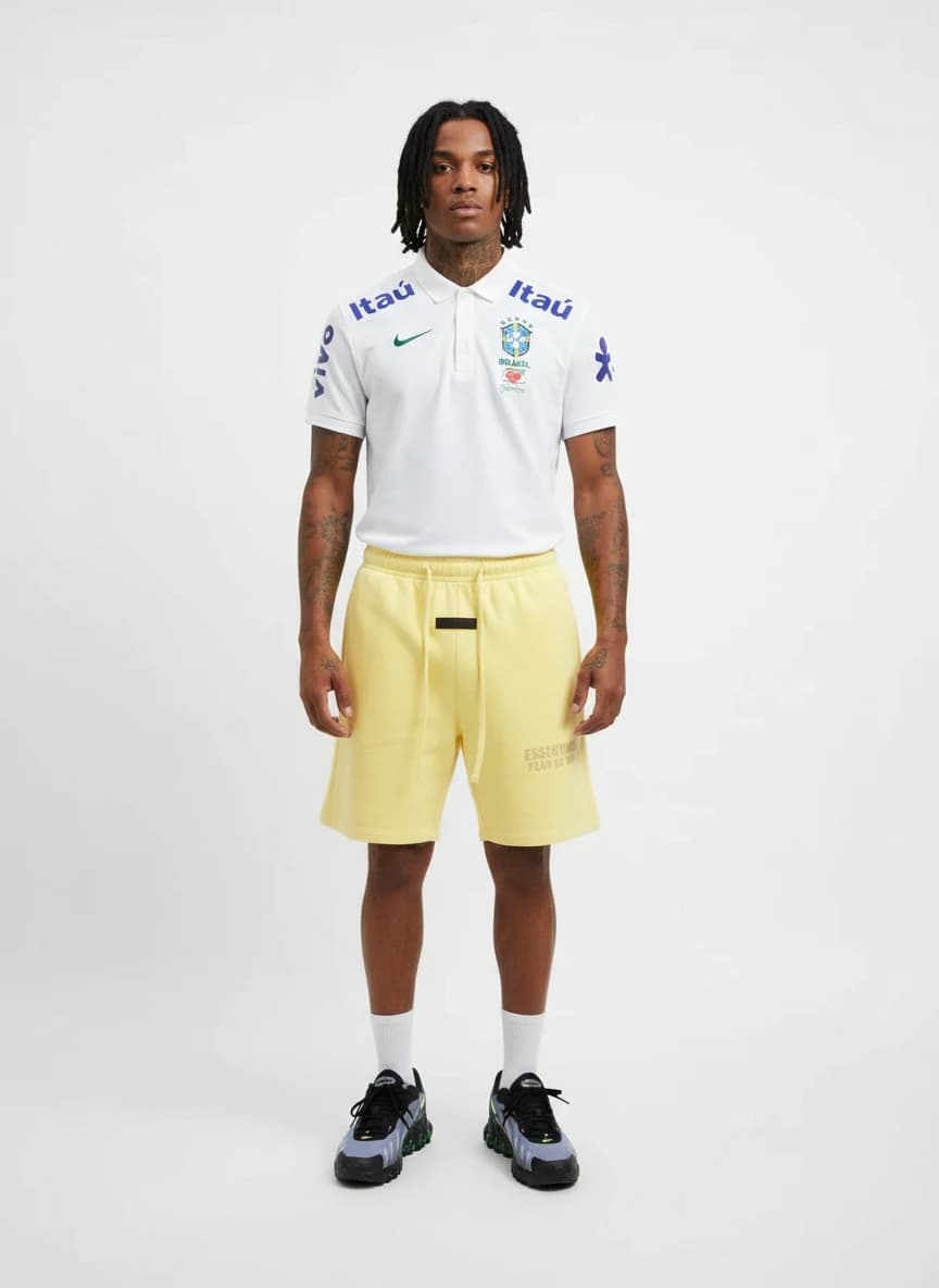 Nike Brazil National Team Polo Shirt - White, Fear of God Essentials Yellow Drawstring Shorts, Nike Air Max Reverb Sneakers in Grey/Black with Green Accents